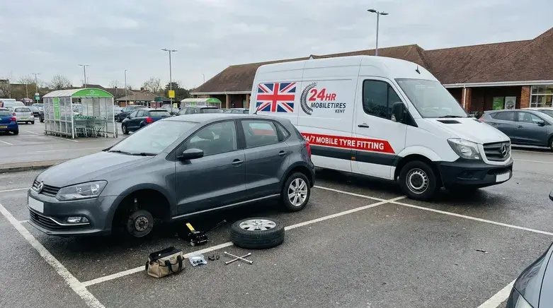 Mobile tyre fitting Ashford technician replacing flat car tyre in supermarket car park with 24hr mobile tyre fitting van